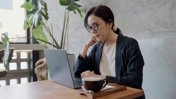 美丽的年轻女子在咖啡馆用笔记本电脑工作