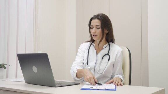 微笑的女医疗助理视频呼叫远程病人的笔记本电脑