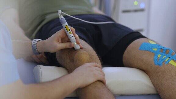 匿名医生手持冲击波激光对患者膝盖进行治疗