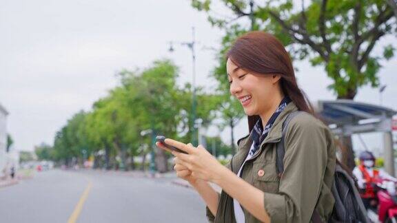 亚洲有吸引力的女人背包客在城市散步时打电话美丽的女人旅游旅行者独自在街上旅行使用智能手机享受花时间在泰国度假旅行