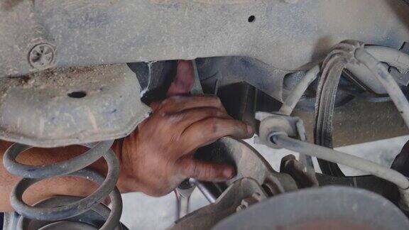 (近景)修车技工正在修车汽车修理店用千斤顶换轮胎手动修理减震器机械车辆机械维修汽车大修维修工程师