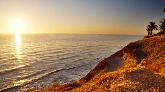 温暖平静海面上的日落海滩山手掌自然场景