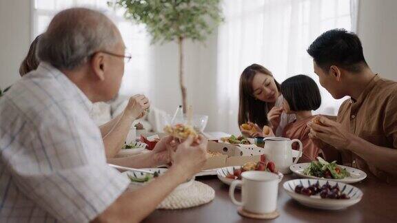 快乐的亚洲家庭在家里的餐桌上一起享受午餐