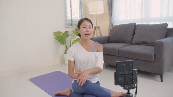 一位美丽的亚洲老师正在用摄像机将课程上传到网上教授学生瑜伽在线学习或在线教学健康的生活方式