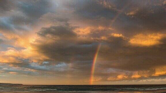 延时拍摄的戏剧性风暴云在日落时在海洋上移动形成明亮的彩虹