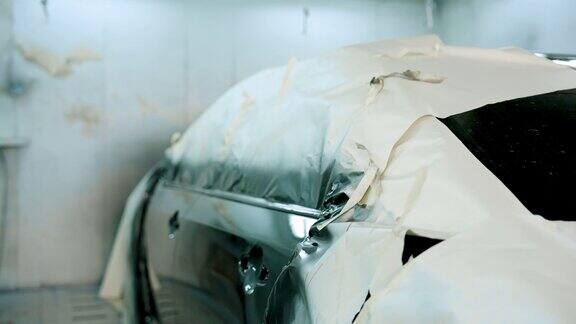 等待重新喷漆的汽车停在喷漆间挡风汽车被纸覆盖在大型车库使用专业机械师的技能防止油漆过量