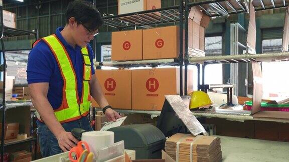 亚洲物流员工使用电脑及条码扫描器追踪货物纸箱或包裹的存货