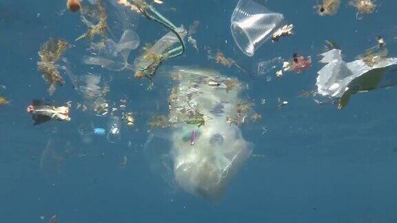 塑料和其他垃圾慢慢漂浮在蓝色的水面上接近珊瑚礁大量污染海洋