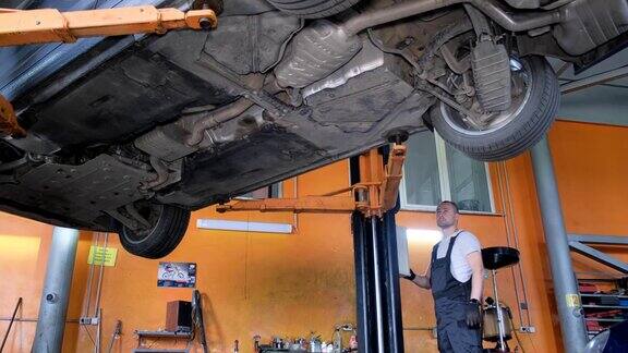 从下面修理汽车的汽车修理工工匠正在修理汽车的底盘