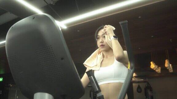 迷人的年轻女性健身在椭圆机健身在健身房