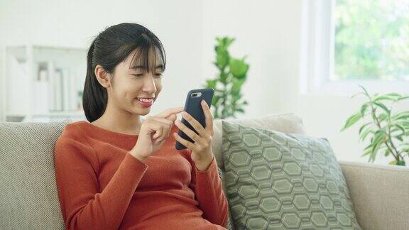 亚洲快乐微笑女孩在家使用智能手机