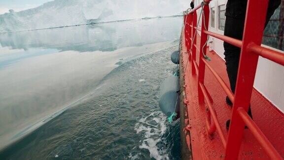 摄影师沿着驶向冰山的红色甲板行走