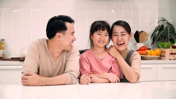 快乐的父母和女儿在厨房对着镜头微笑