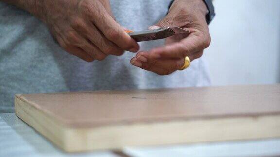 在粘贴到胶合板上之前专业技术人员用切刀装饰纸张的边缘