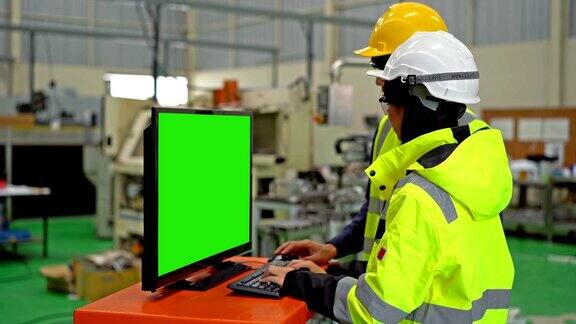 在一家重工业制造工厂工作的男女工程师使用绿色屏幕的电脑