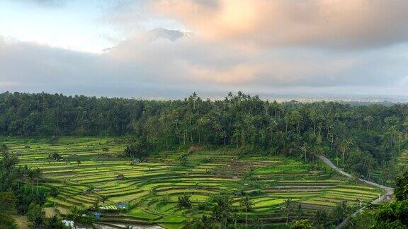 印尼巴厘岛阿贡火山的延时移动云日落场景前景是稻田梯田