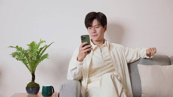 一个亚洲年轻人在沙发上玩手机