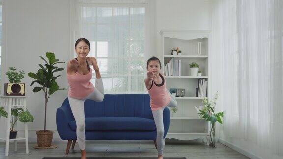 母女俩正在家里练习瑜伽舞者式或Natarajasana