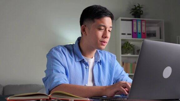 年轻的亚洲商人坐在家里用笔记本电脑工作亚洲男子使用笔记本电脑上网学习信息