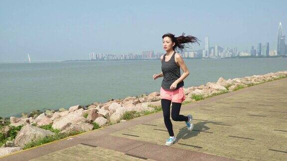 年轻的亚洲女人在海边跑步