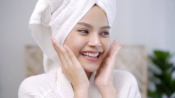 一位头上裹着白色毛巾的亚洲美女面带微笑地看着镜头