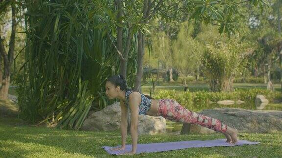 年轻的亚洲女人在户外做瑜伽美丽的阳光下在公园里