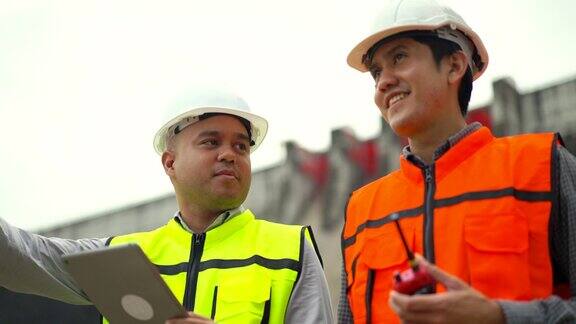 自信的亚洲两名维修工程师在工地用平板检查水坝、水电站和灌溉系统在大型建筑项目工作的团队工程师和灌溉在大建筑项目工作的团队工程师