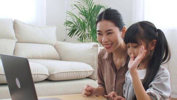 亚洲家庭与女儿学习在笔记本电脑和妈妈在客厅