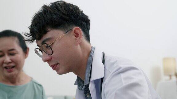 年轻的亚洲男性医生向老年病人解释药物