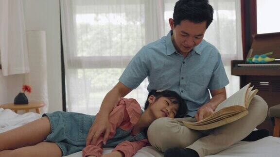 亚洲成年爸爸在家给可爱的小女儿读童话故事