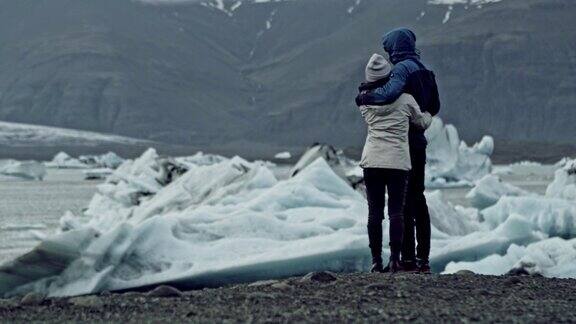 一对情侣拥抱着看着冰川泻湖
