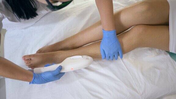 腿部脱毛由专业美容师在水疗沙龙治疗室用激光设备为女性患者进行足部脱毛
