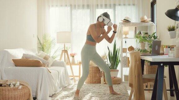 年轻的亚洲女运动员戴着虚拟现实耳机在家里的客厅进行拳击训练饮食和健康减肥