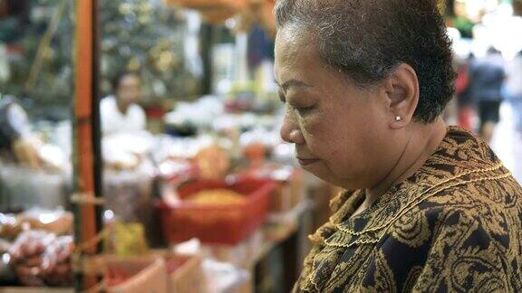 一位高级女士在中华城曼谷购买食物