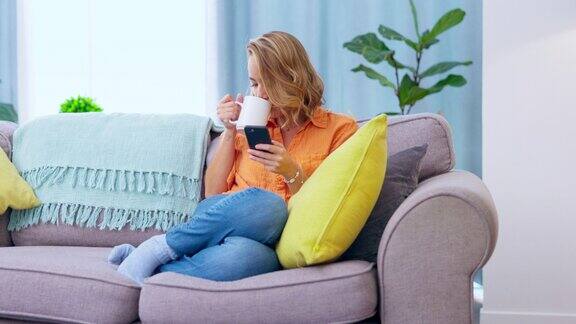 手机咖啡和亚洲女人在沙发上放松社交媒体滚动互联网和在线网络或聊天年轻人坐在沙发上和智能手机、手机或移动应用一起喝平静的茶或饮料