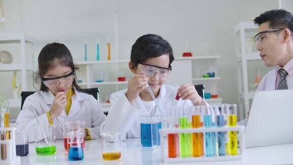 小学科学课堂:亚洲儿童在科学实验室实验台上统一学习各种颜色的试管玻璃水