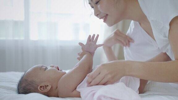 亚洲年轻母亲在床上玩她的婴儿家庭关系