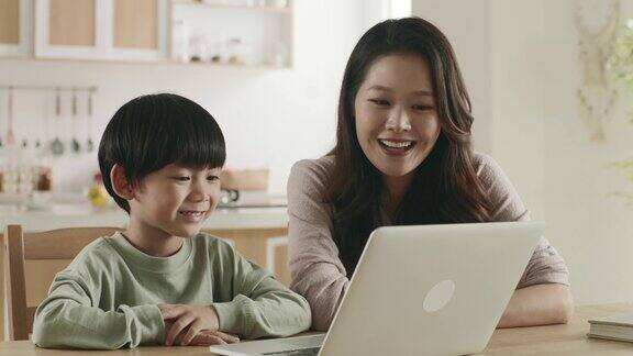 年轻的亚洲母亲和儿子在家里看电影