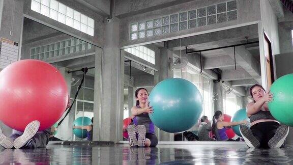 人们在健身房用五颜六色的普拉提球锻炼