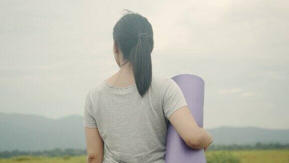 美丽的亚洲白人女性站在美丽的山景瑜伽垫在上午
