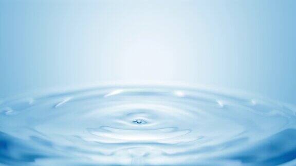 蓝色的水滴落在清澈的液体表面形成圆圈