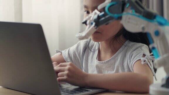 一名亚洲女孩用笔记本电脑学习控制机械臂