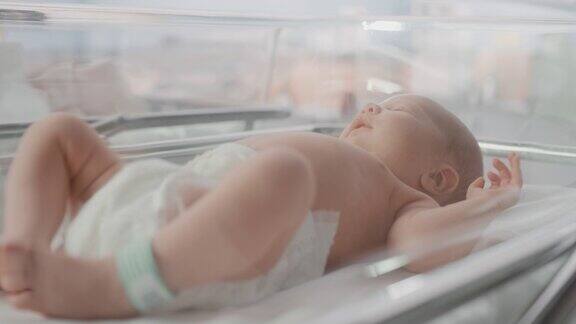 新生儿出生后躺在产科病房的摇篮里的肖像可爱的新生儿呼唤母亲感觉精力充沛失眠分娩和医疗诊所概念