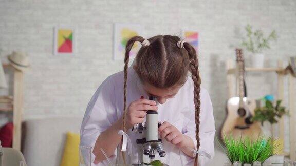 十几岁的女孩通过显微镜看的肖像一个学校项目的特写