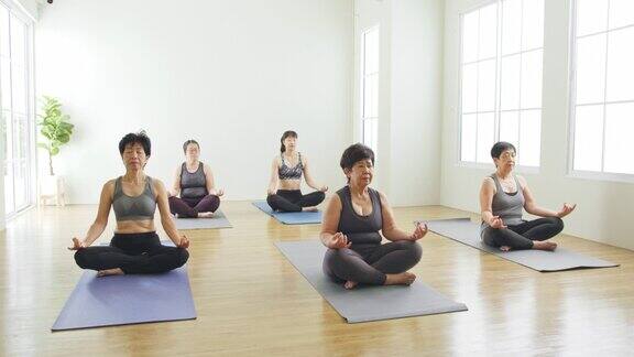 一群亚洲女性在健身房进行多代呼吸练习和瑜伽练习