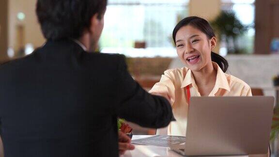 年轻的亚洲女性面试官和面试者握手的肖像商务人士在现代办公室握手问候协议概念