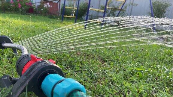 灌溉洒水器在花园里浇灌着绿色的草坪