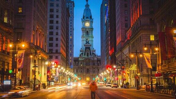 美国宾夕法尼亚州费城地标性历史建筑市政厅的夜间交通车辆和拥挤的行人穿过城市街道