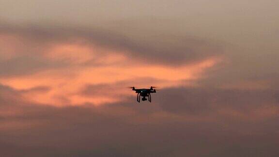 带数码相机的无人机四架直升机在日落上空盘旋