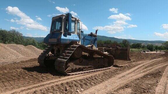 推土机在尘土飞扬的野外道路施工中平整地面